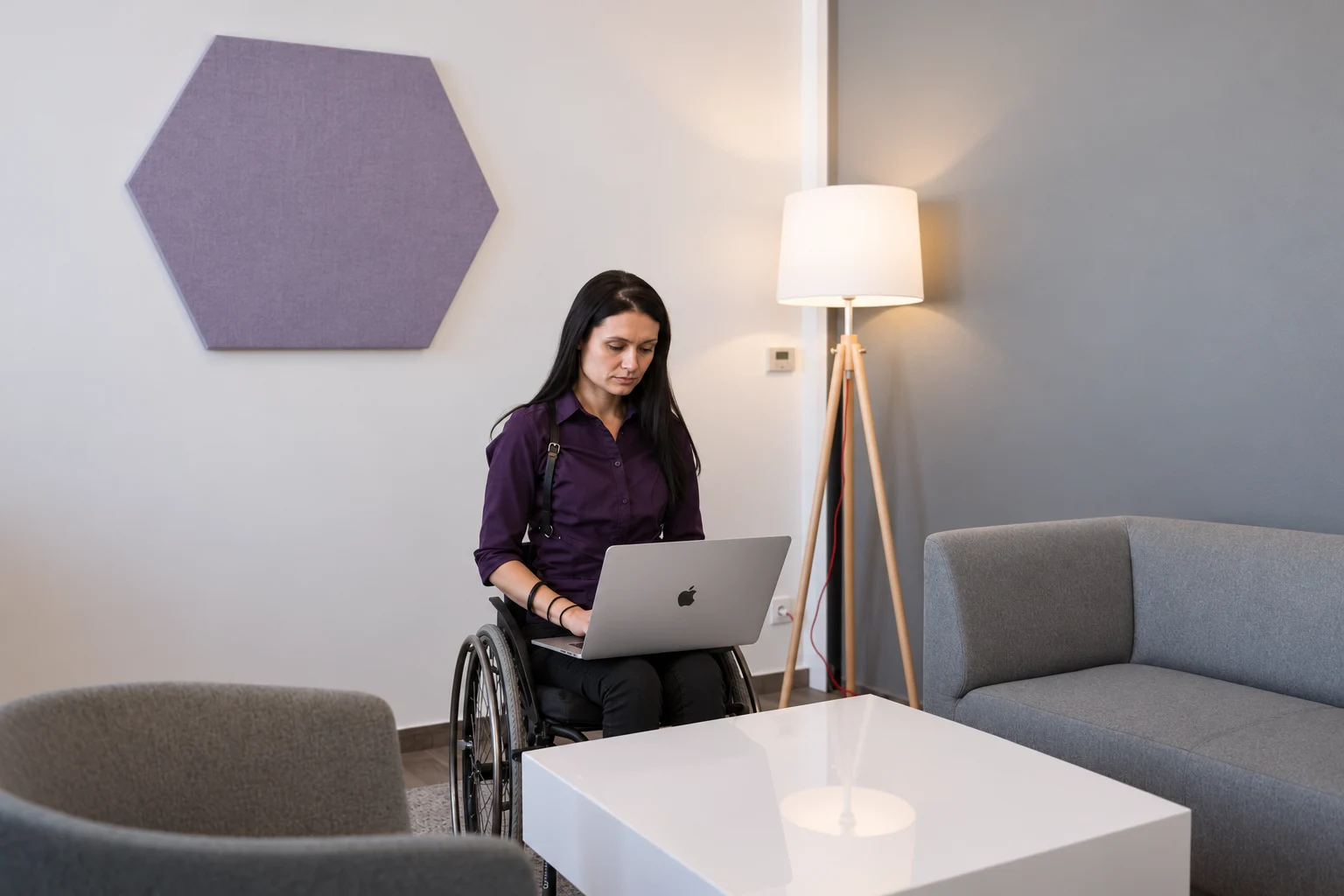 Wheelchair user working with a MacBook in a contemporary setting