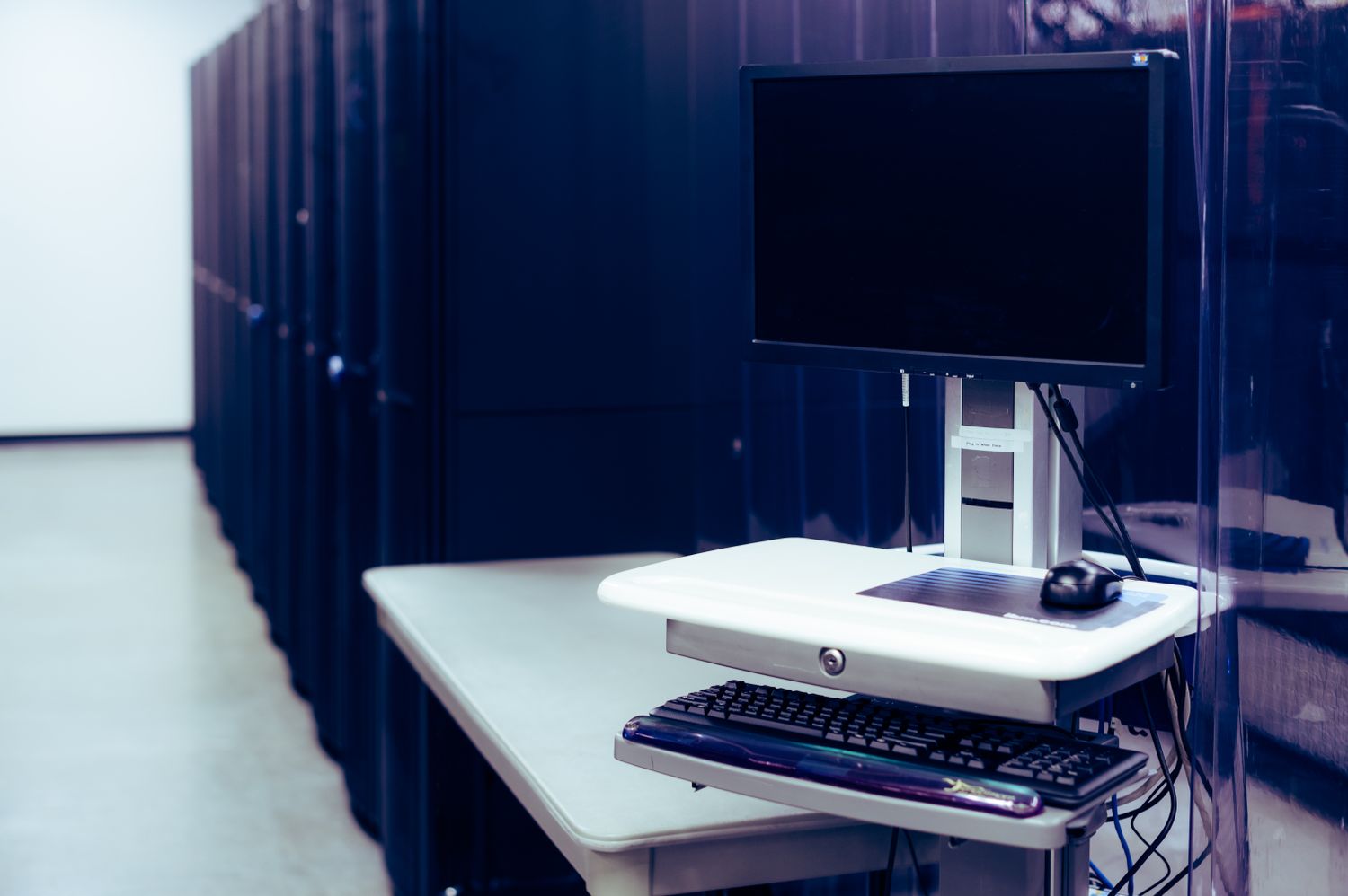 Console de operação ao lado de uma sequência de racks em um datacenter.