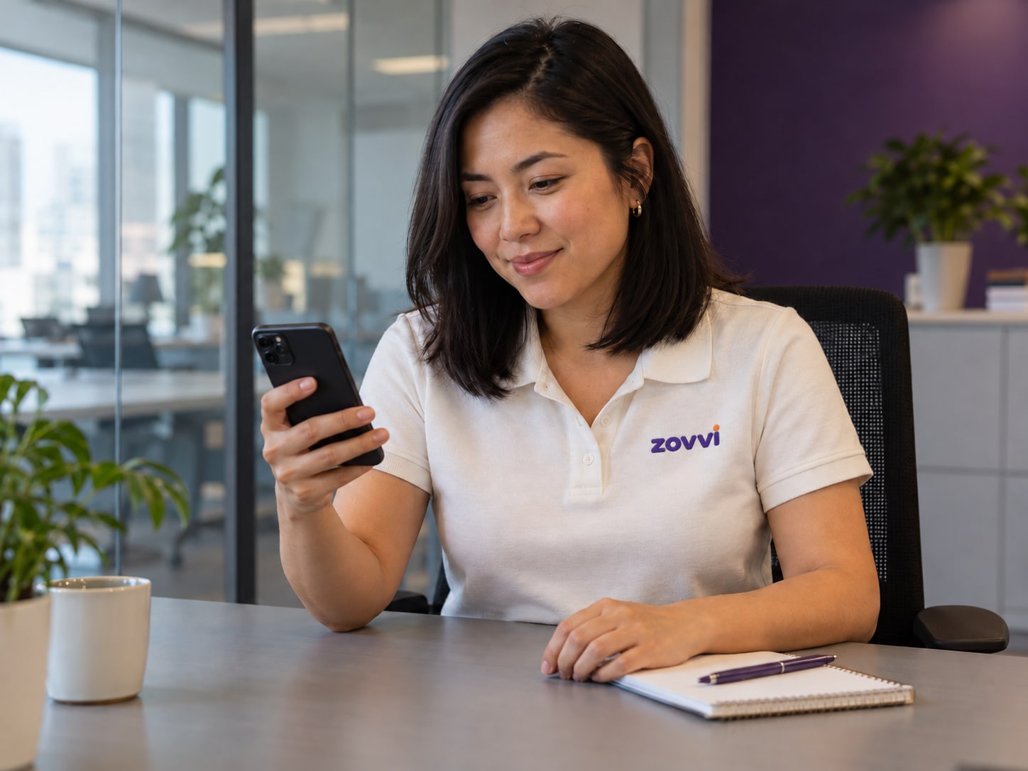 Professional in a Zovvi uniform checking messages on a phone.