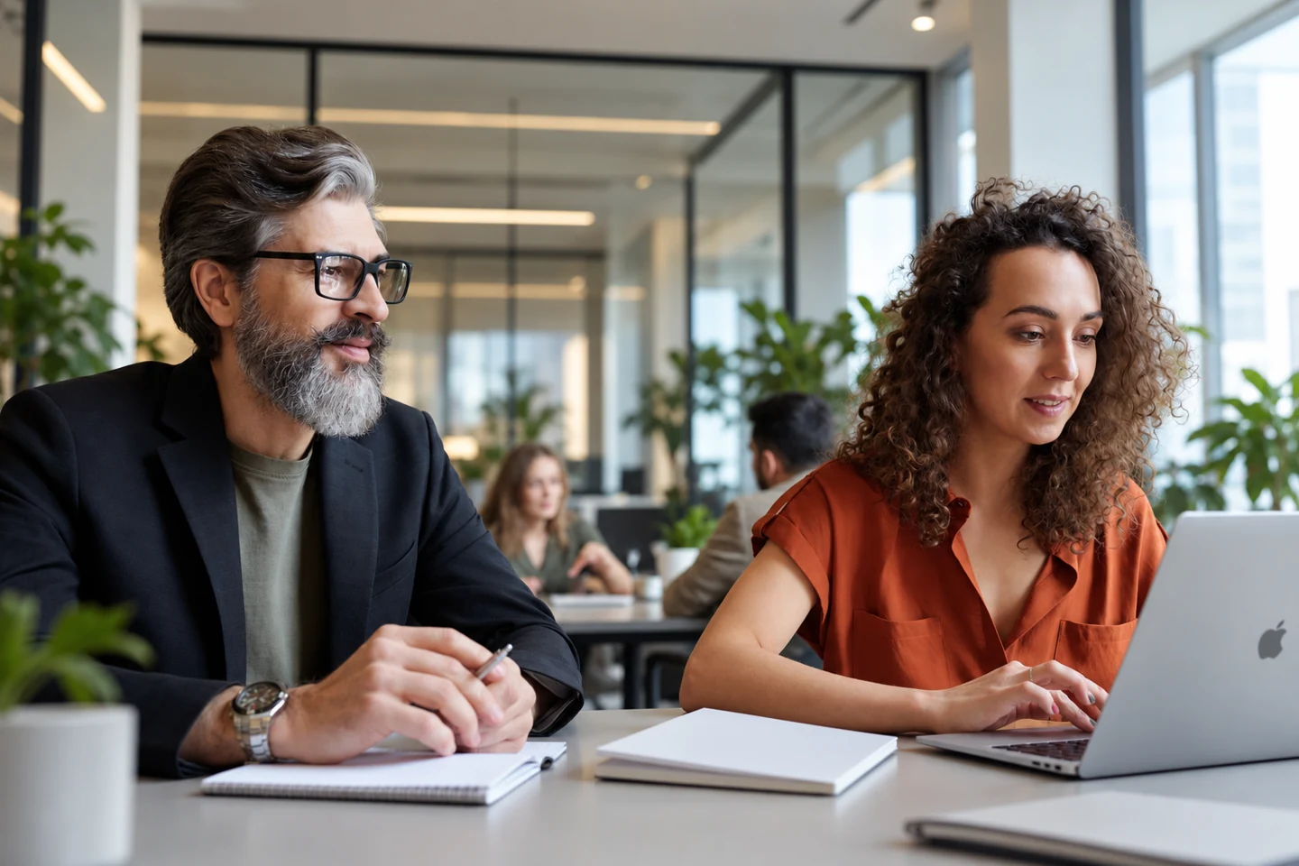 Two professionals planning a project with a laptop and notes in a contemporary office